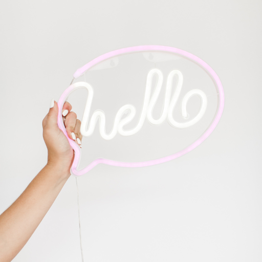 Hand holds out neon sign that reads Hello.